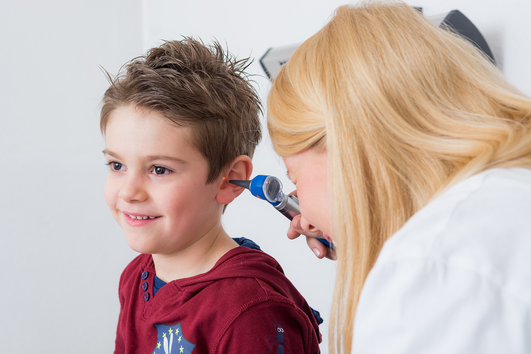Ärztin untersucht das Ohr eines Jungen.