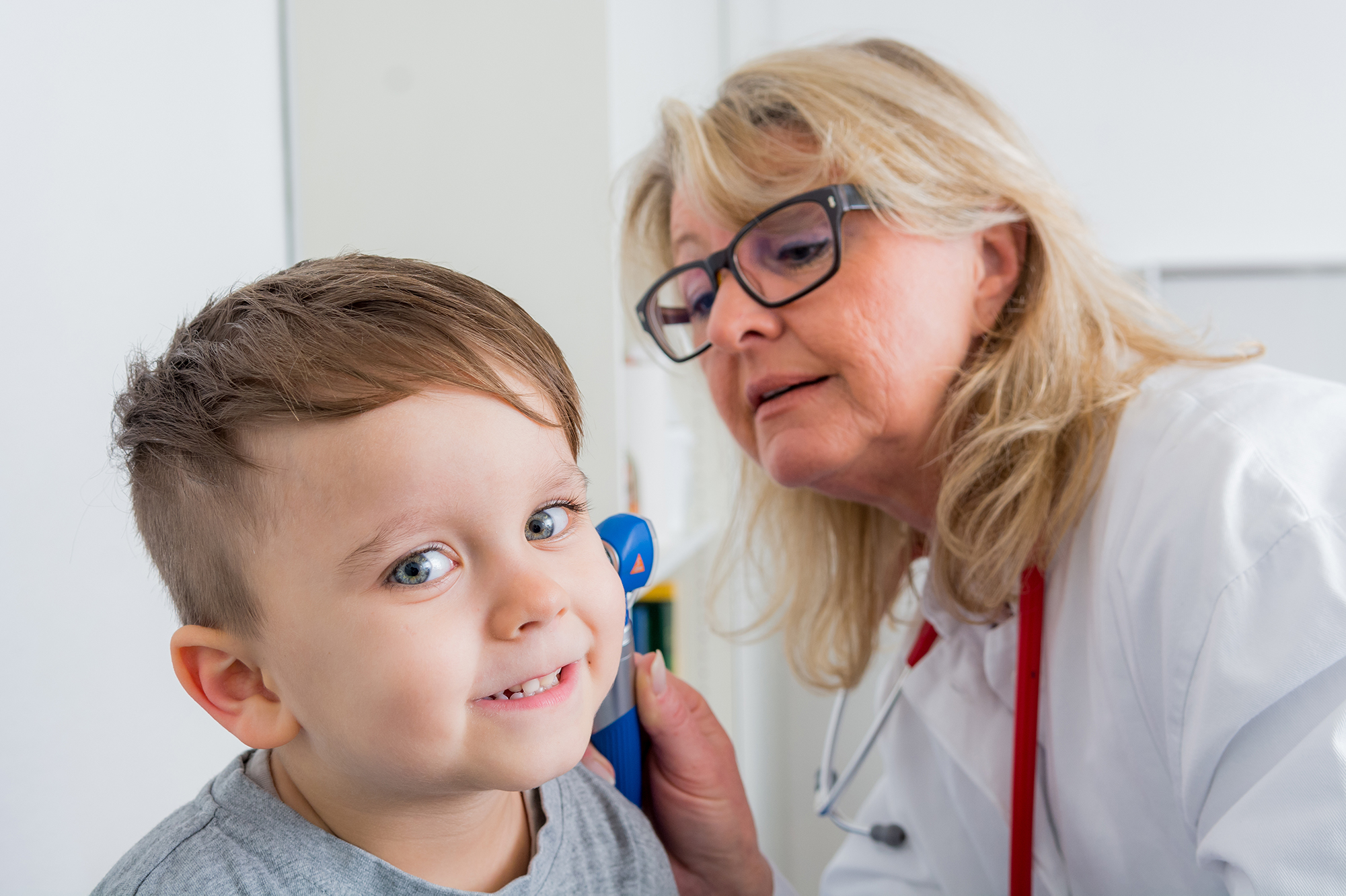 Ärztin untersucht das Ohr eines kleinen Jungen.
