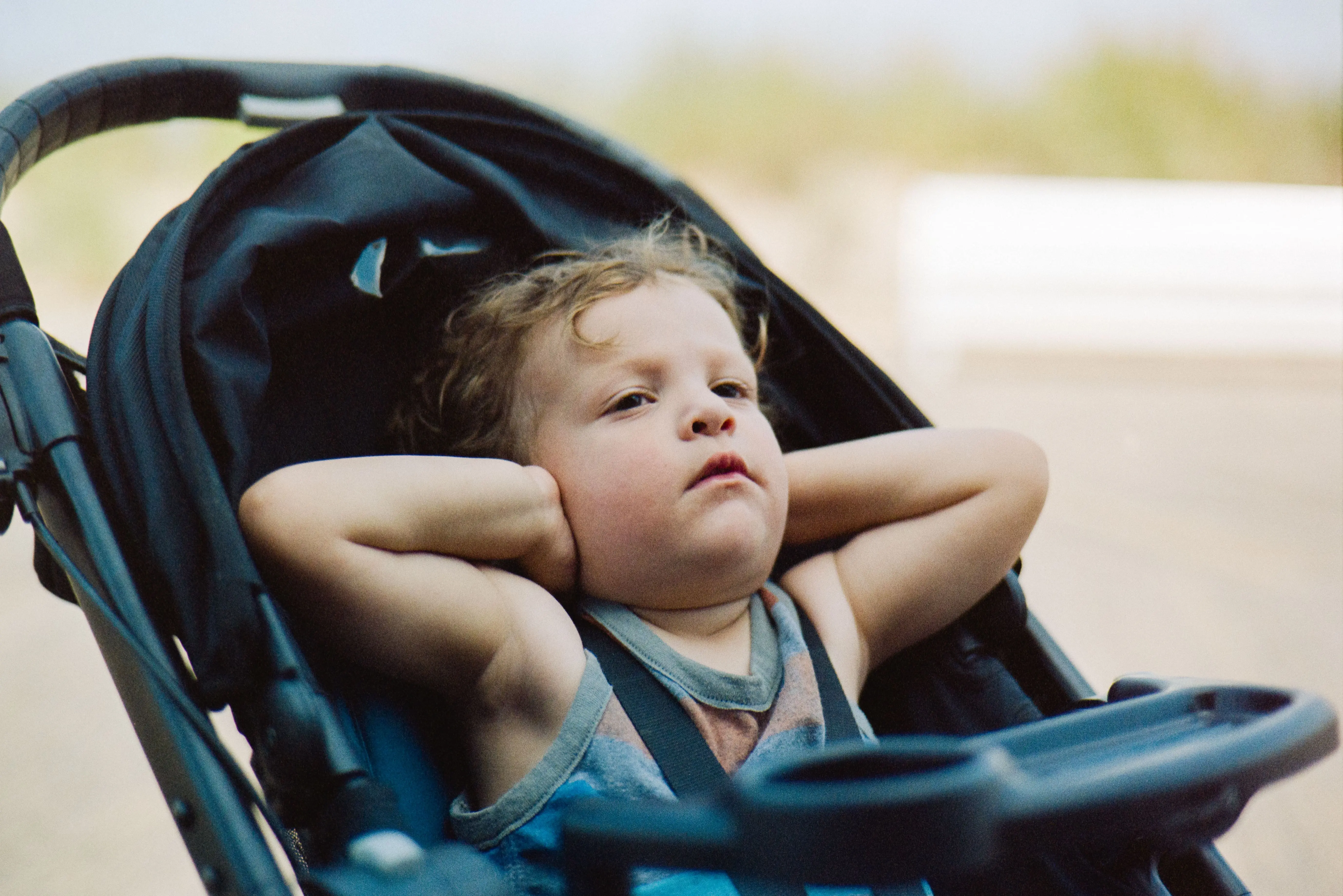 Kleinkind in einem Buggy hält sich die Ohren zu, da es Ohrenschmerzen hat.